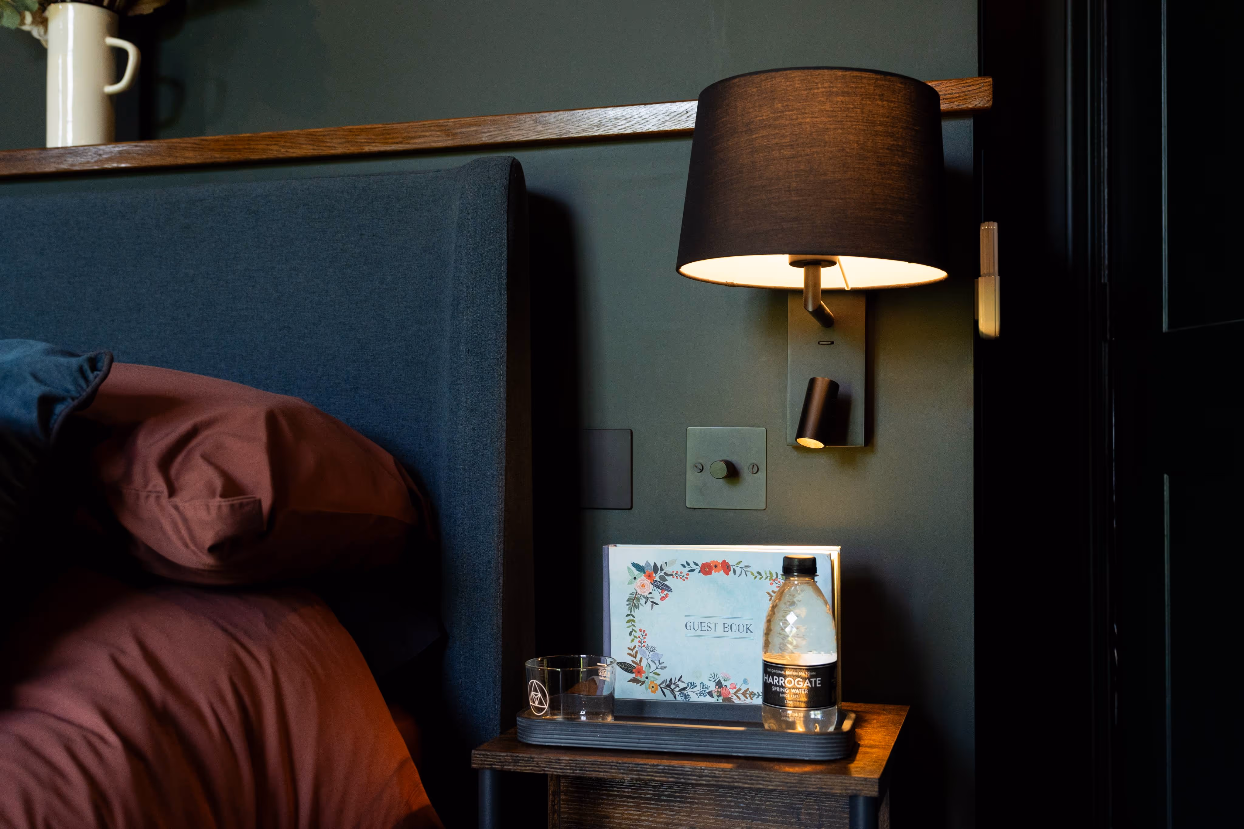 The annex bed side table with hung wall light and complimentary water