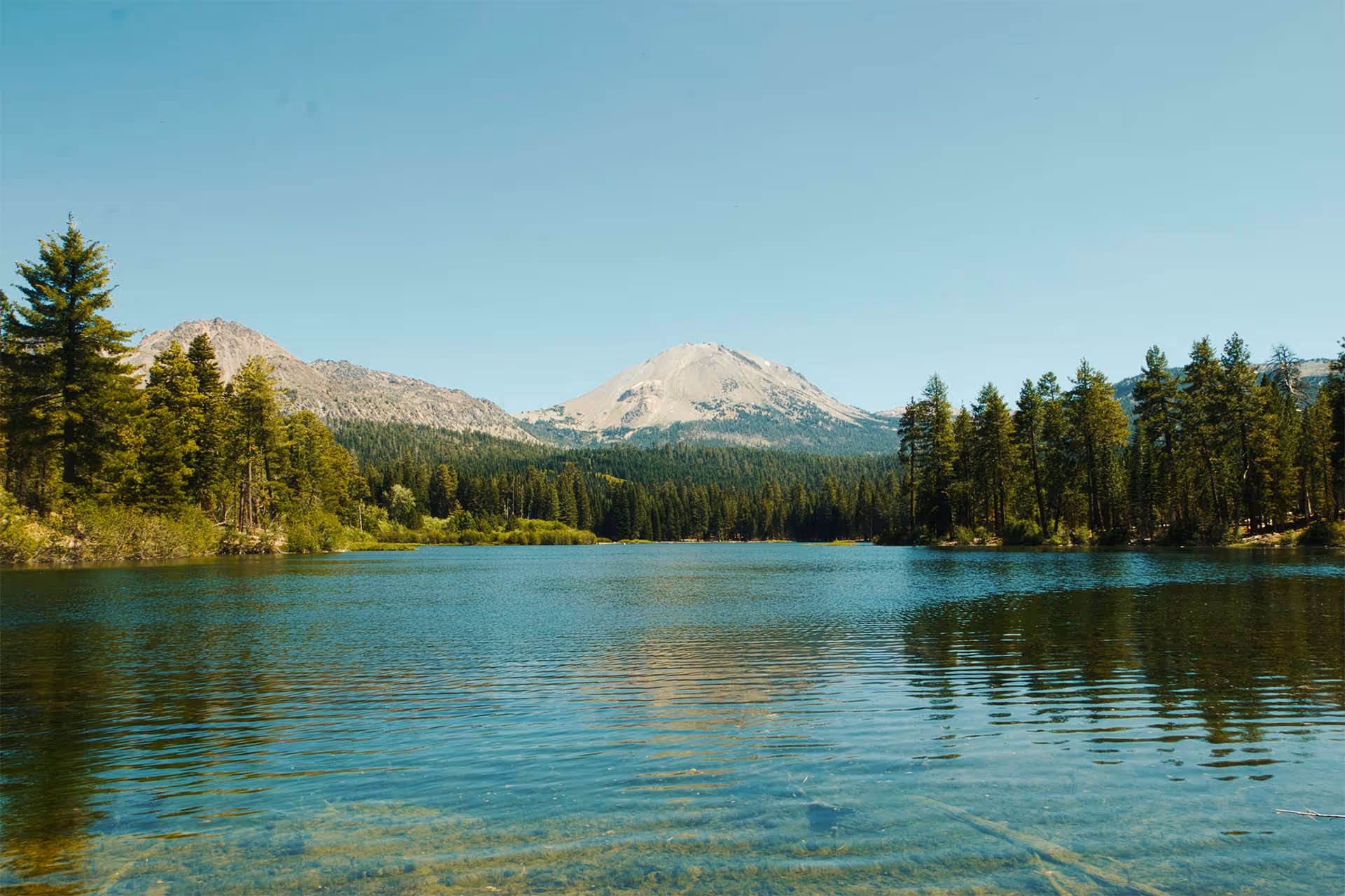 Lac entouré d'une foret avec une montagne en arrière-plan