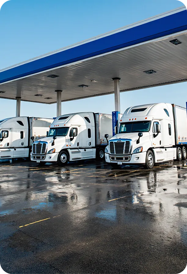Row of white trucks at gas station.