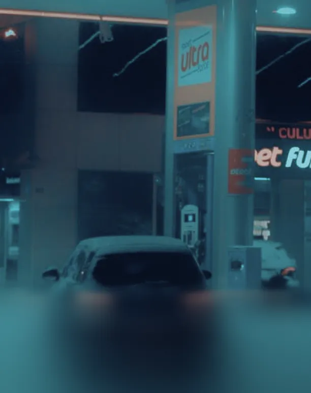 Snow-covered car at gas station.