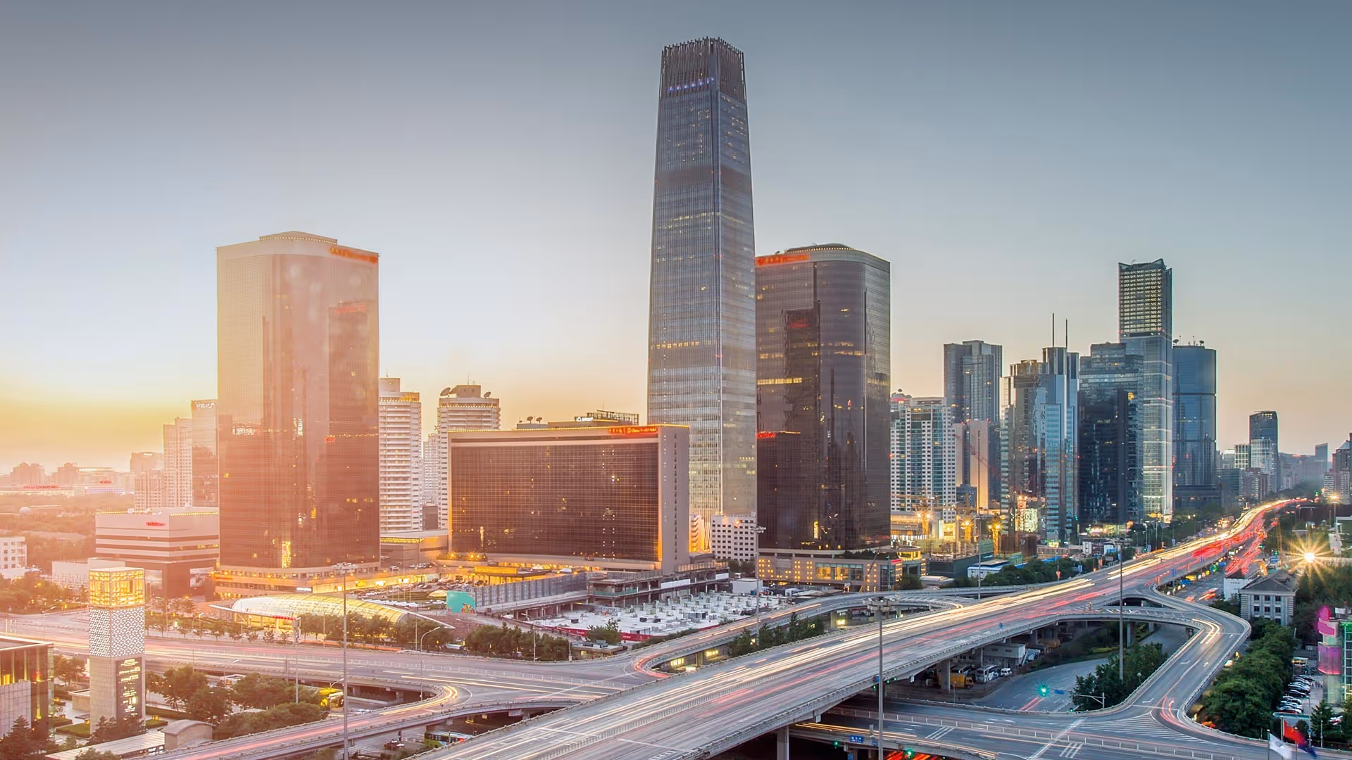 Stadtbild von Beijing mit modernen Hochhäusern und vielspuriger Autobahn bei Sonnenuntergang.
