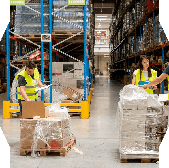 Warehouse workers in yellow safety vests inspecting and organizing pallets of boxes wrapped in plastic.