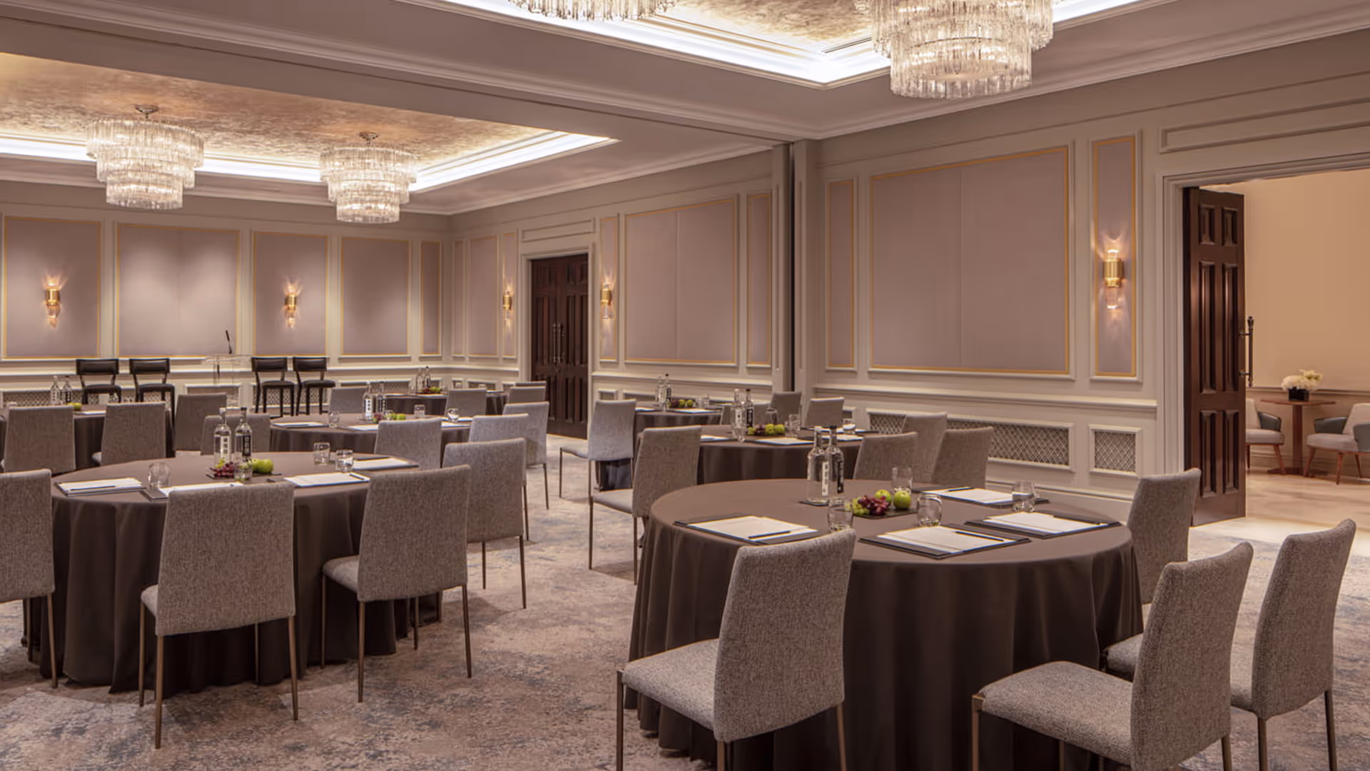 Four Seasons conference room with 1902 Iver stacking chairs, round tables, dark tablecloths, floral centrepieces, and ornate chandeliers in a panelled interior