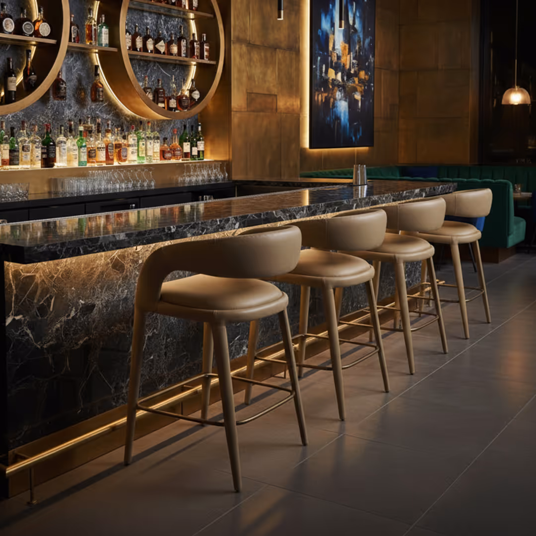 Stylish bar interior with dark marble counter, 1902 Sorana tan bar stools, and circular gold shelving framing liquor bottles and cityscape artwork