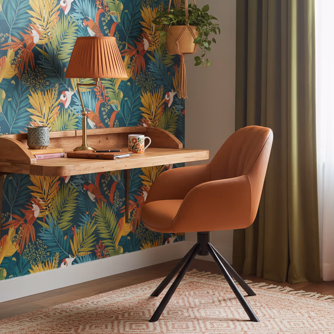 Boutique hotel guestroom with 1902 Sarma burnt-orange desk chair, tropical wallpaper, floating desk, and pleated lamp
