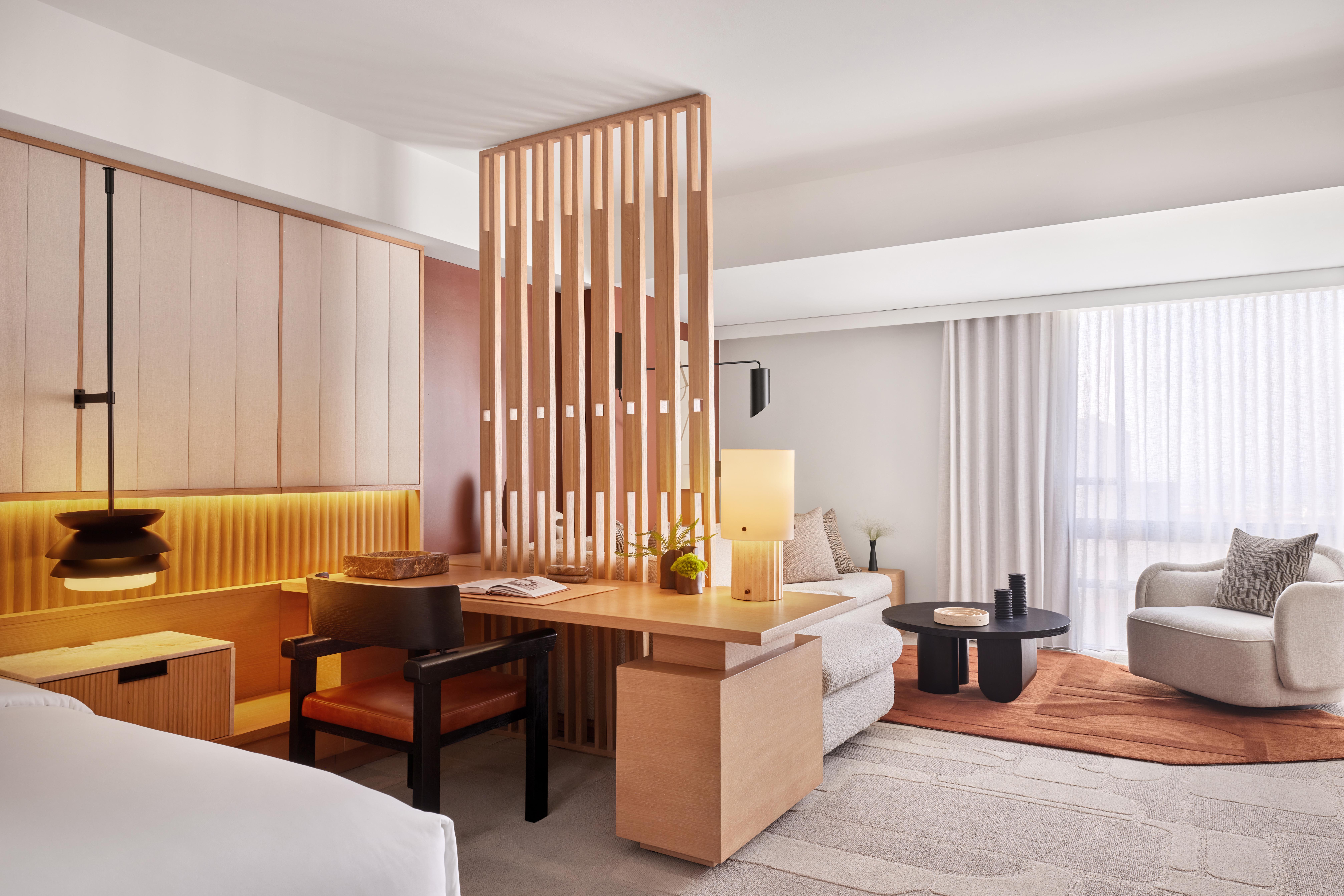 Bright, modern guestroom at The Jay Autograph Collection with warm wood accents and inviting lounge space.