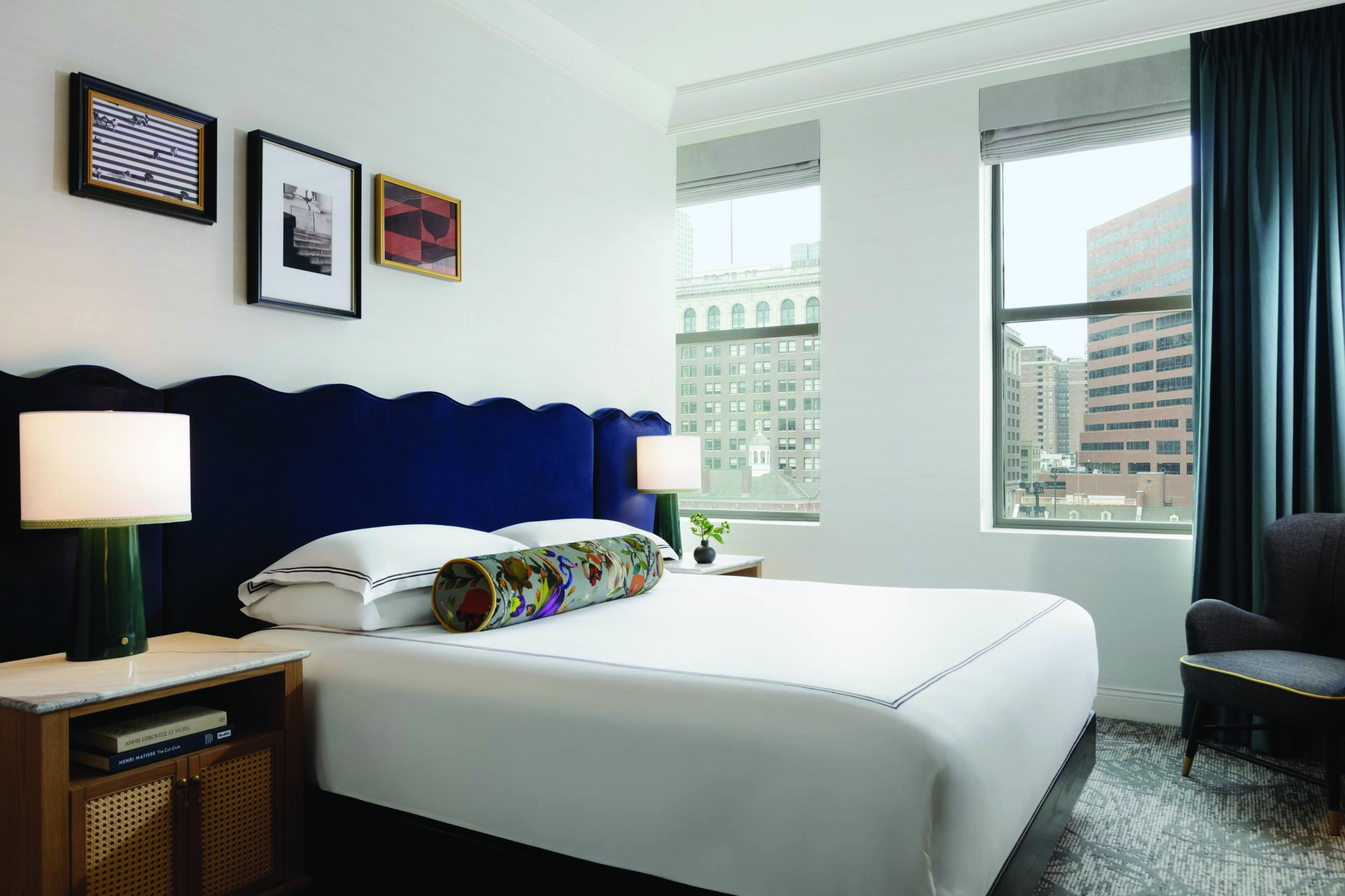 Elegant guestroom featuring a sculpted navy headboard, tailored bedding, and refined wood bedside furniture with modern lamps.