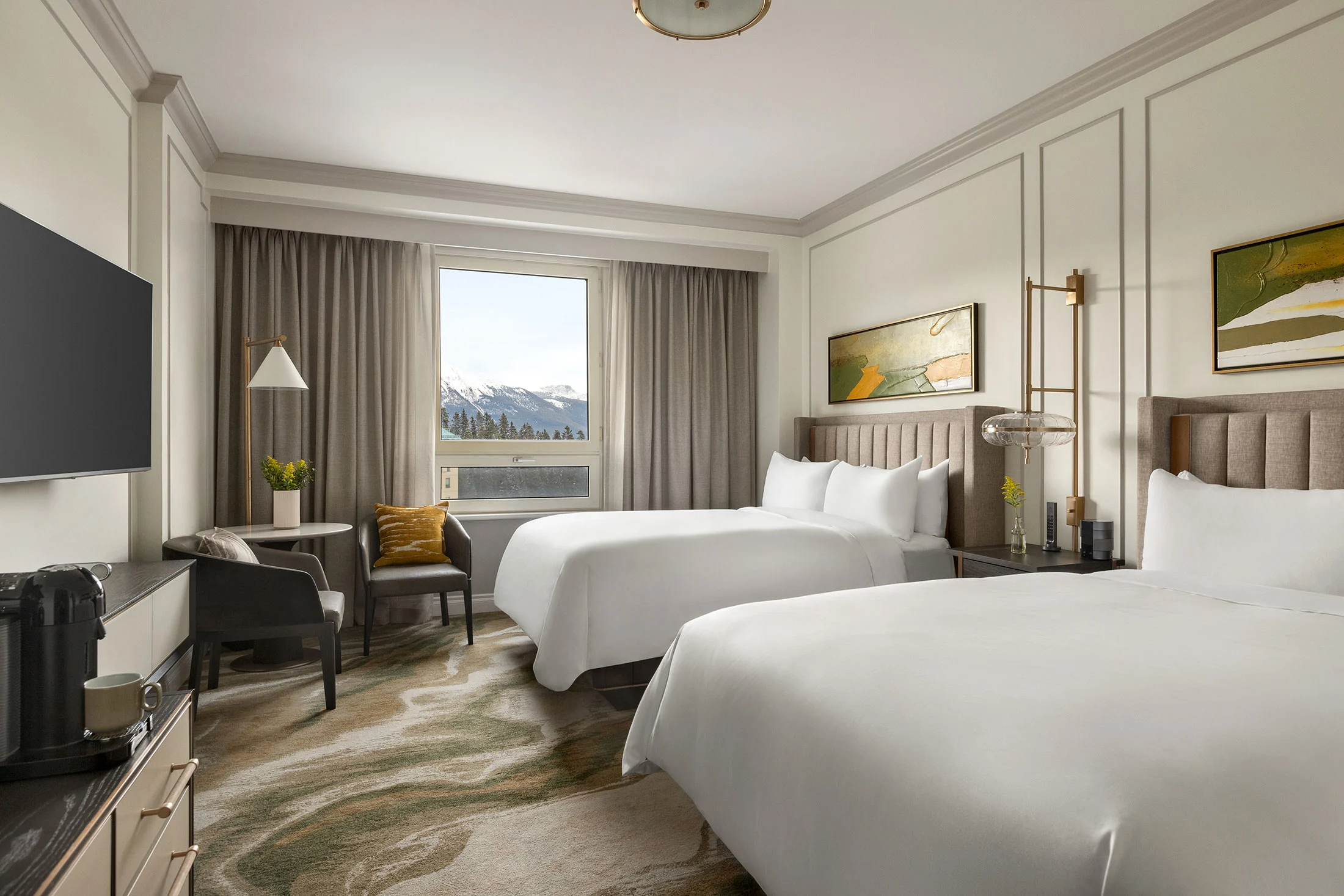 Sophisticated mountain-view guestroom with plush twin beds, tailored headboards, and elegant wood furnishings in soft neutrals.