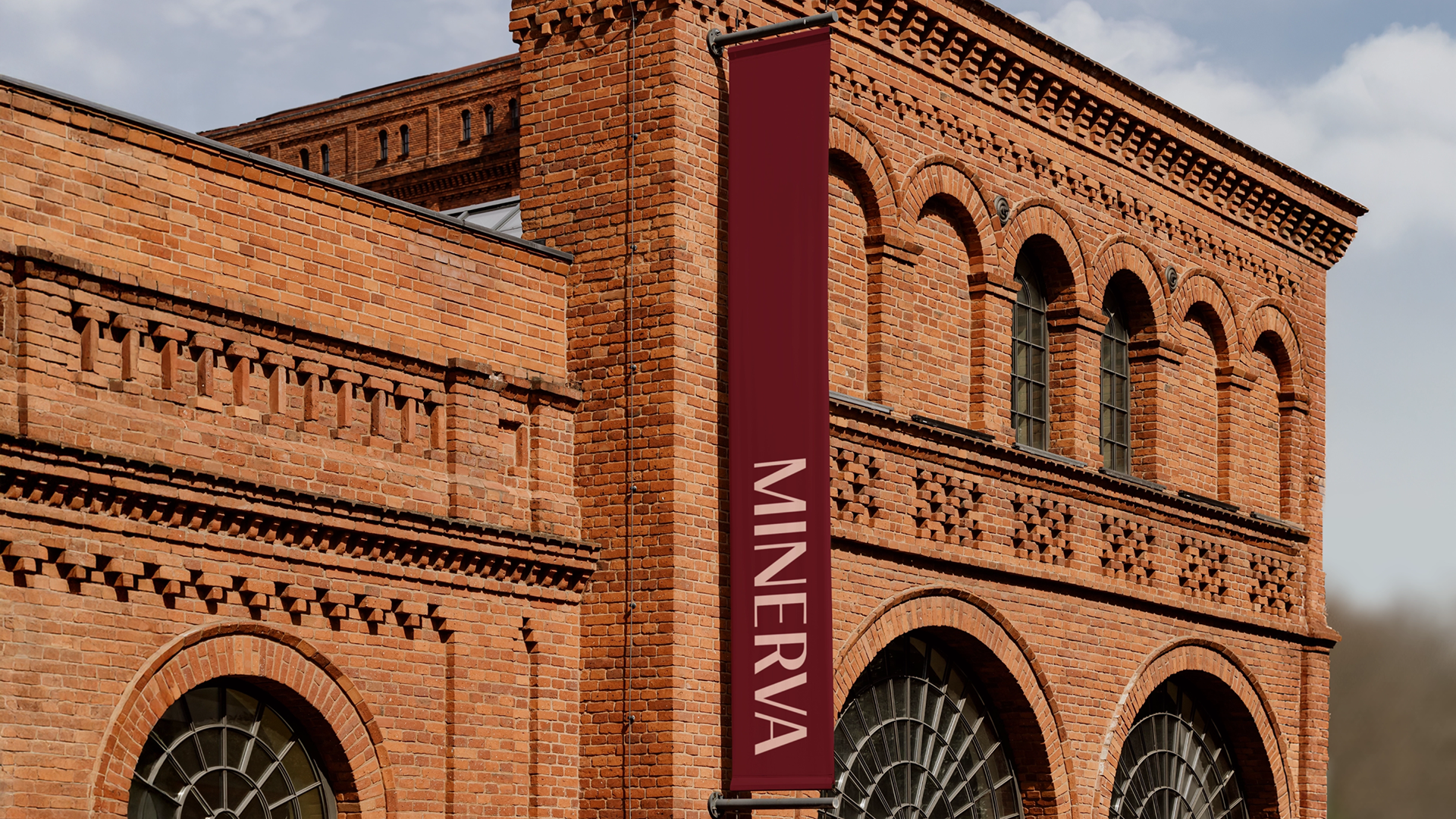 Laptop and smartphone on an orange fabric chair displaying the Minerva website, with pages on diversity and services.