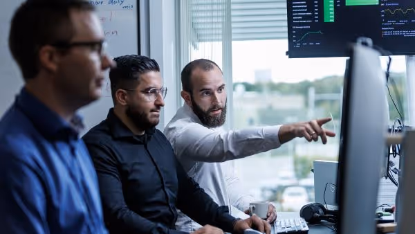 A group of men sitting around a computer screen.