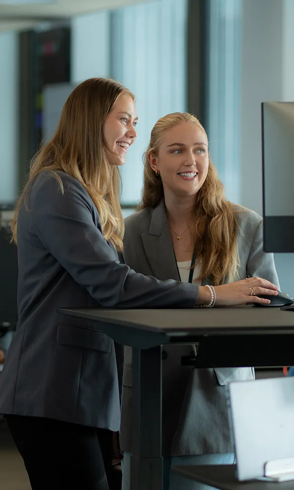 Two women standing at a desk looking at a computer screen