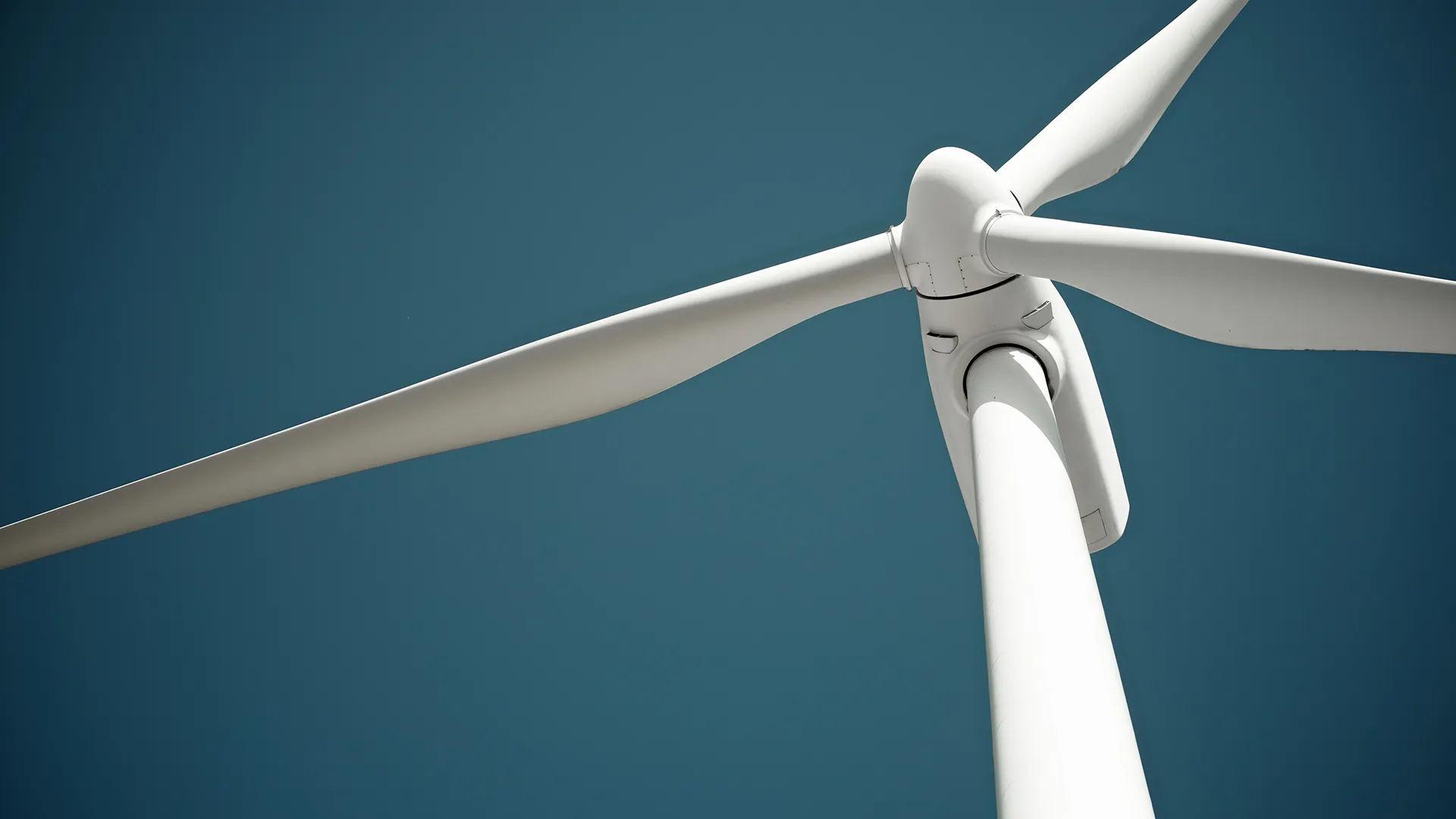 Close-up view of a white wind turbine against a clear blue sky.