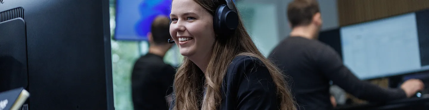 Smiling Norlys Energy Trading Employee at her desk with a headset on