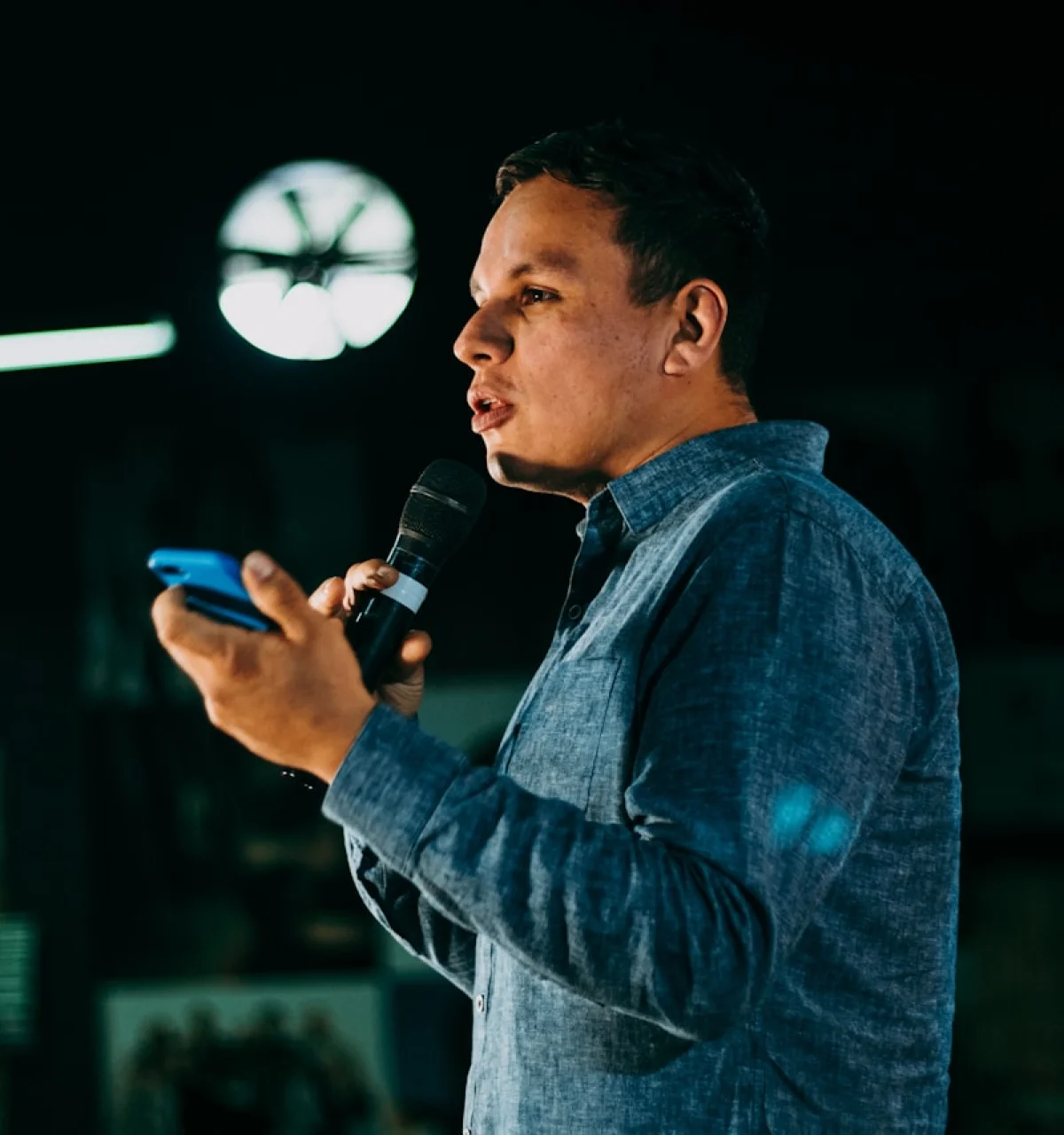 Man holding microphone delivering a talk on stage.