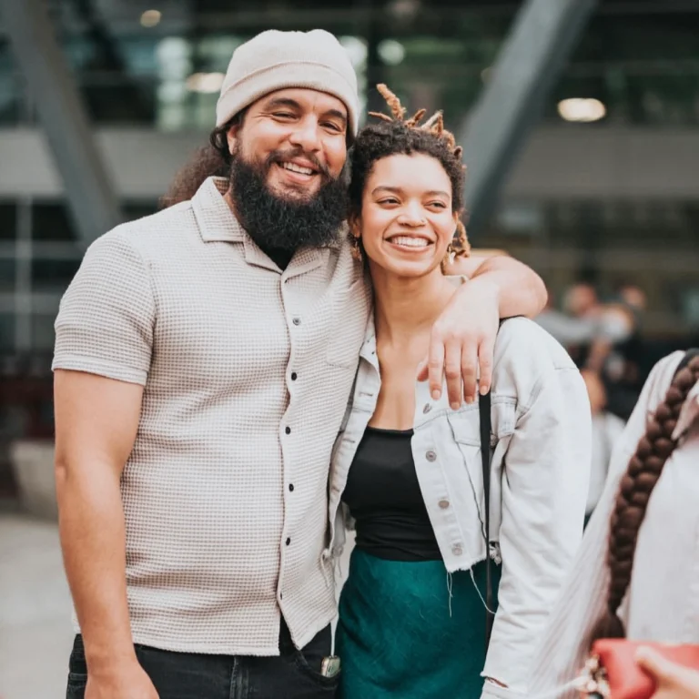 Smiling couple embracing while standing outdoors.