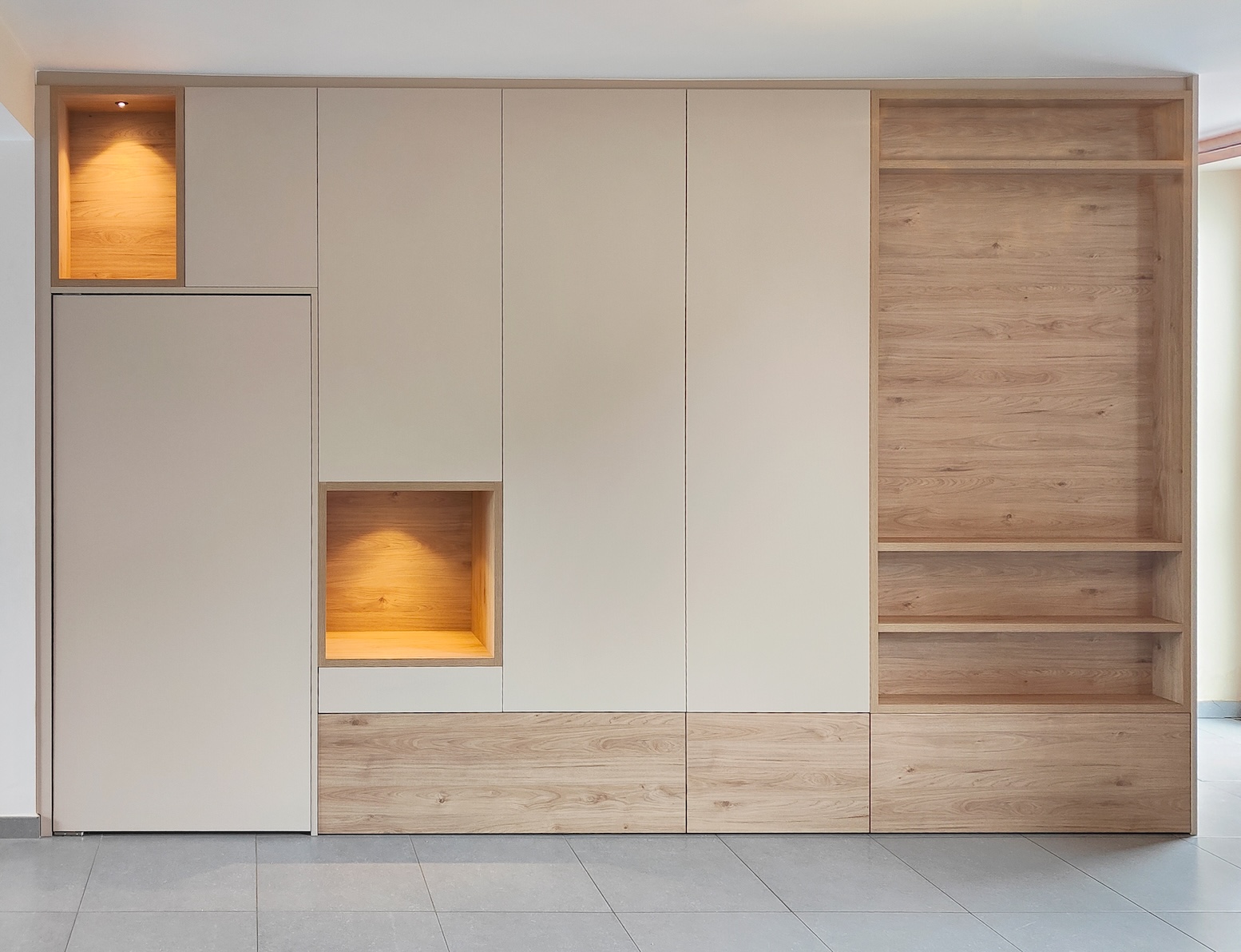 Armoire murale moderne intégrée en bois clair et panneaux beiges avec niches éclairées et étagères ouvertes.
