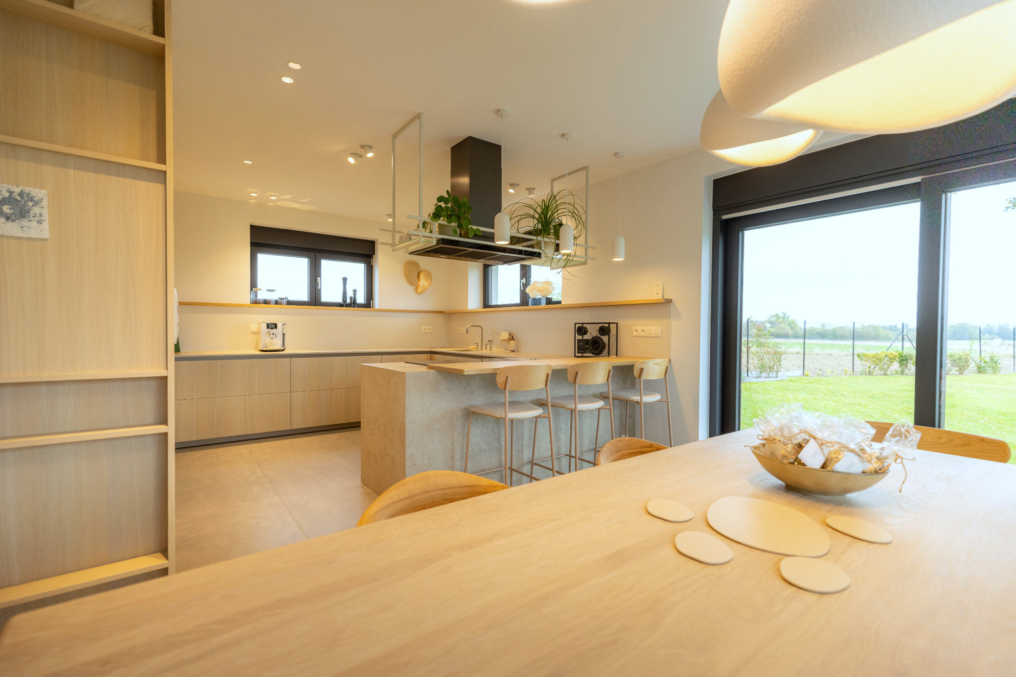 Cuisine sur mesure PENATE en chêne clair avec un îlot central et des finitions noires.