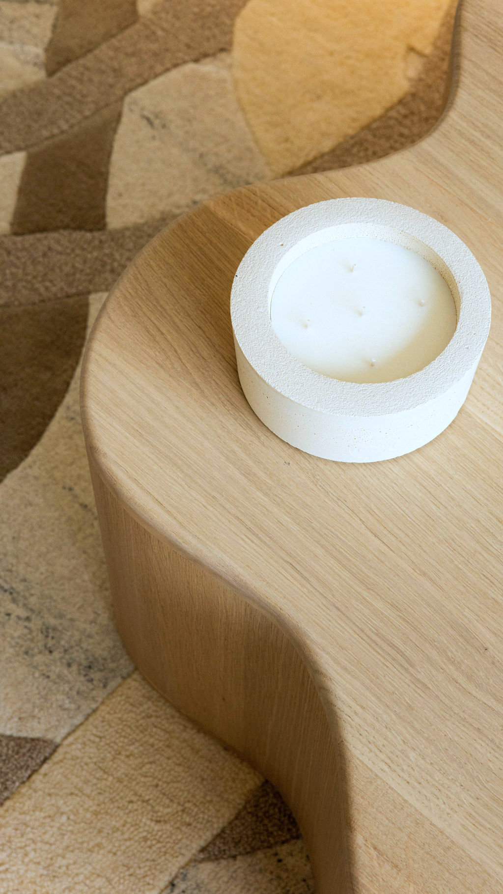 Cuisine moderne lumineuse avec comptoir en bois, plaques de cuisson, deux tabourets et armoires en bois clair.