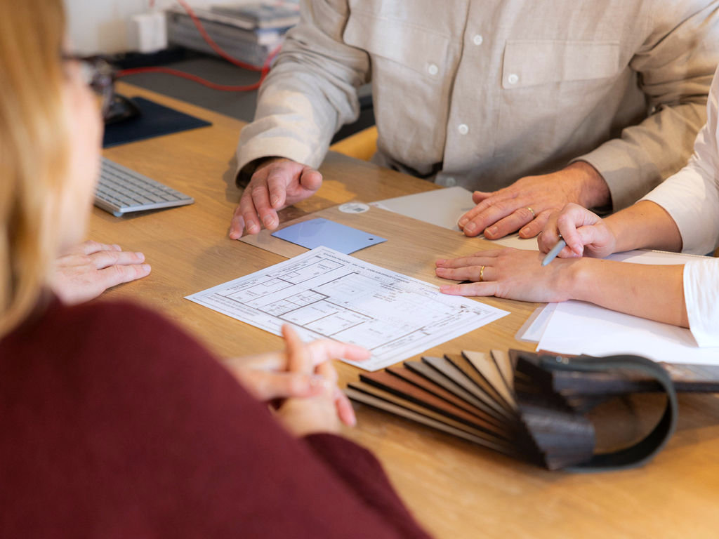 Main d'un designer dessinant une esquisse de meuble sur mesure sur un carnet.