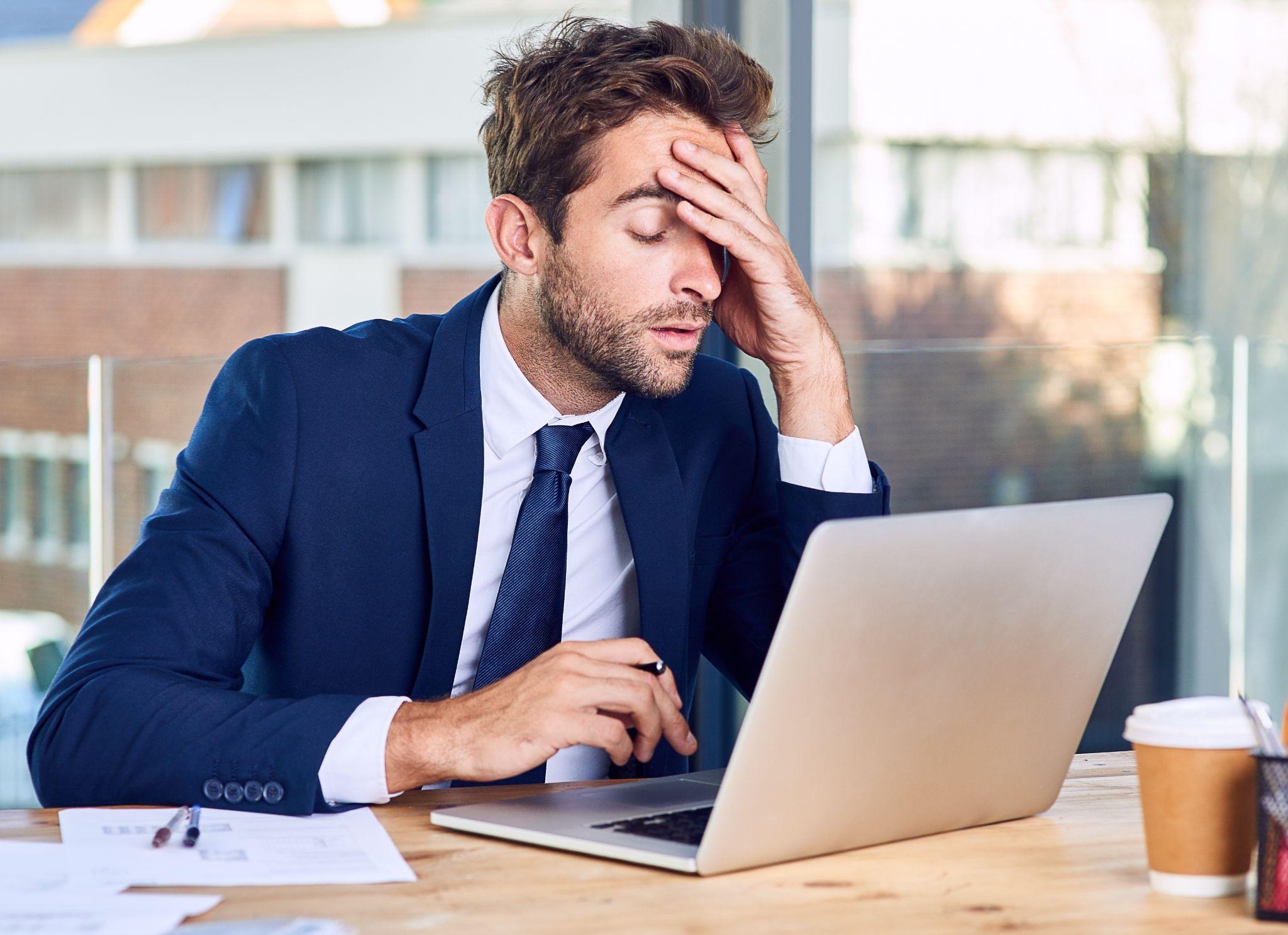 Employee experiencing burnout while working on laptop in office