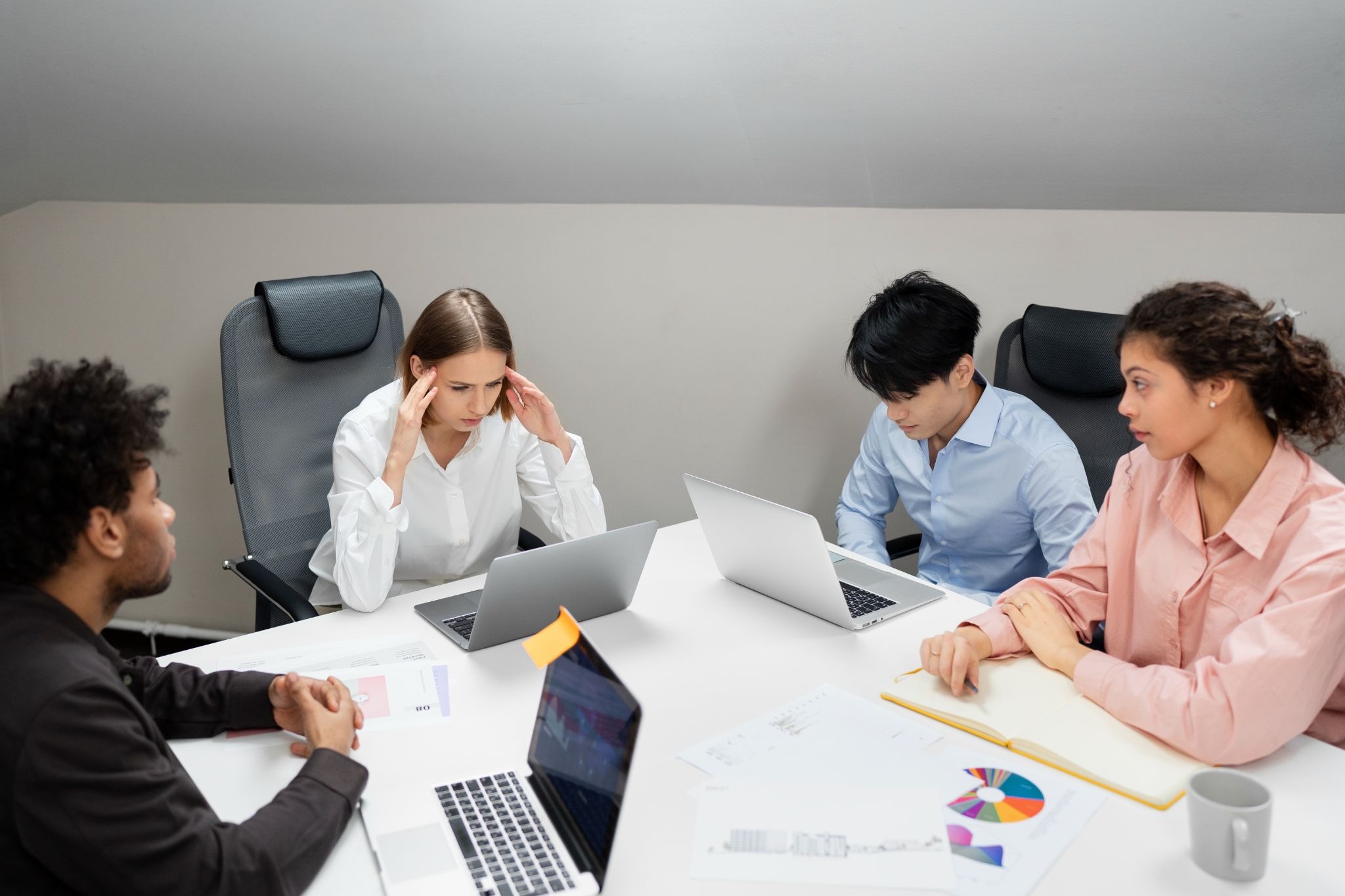 Employees showing early signs of workplace burnout and emotional exhaustion during a stressful office meeting