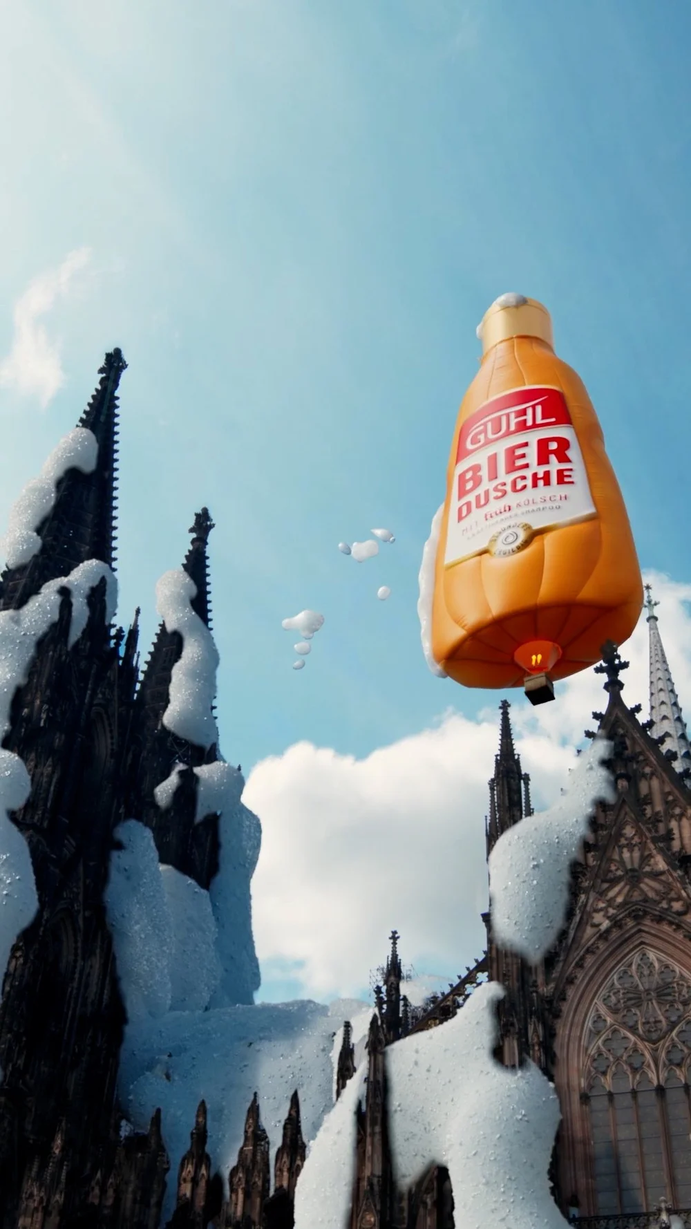 Gothic cathedral with foam covering its spires and a hot air balloon shaped like a beer bottle floating above.