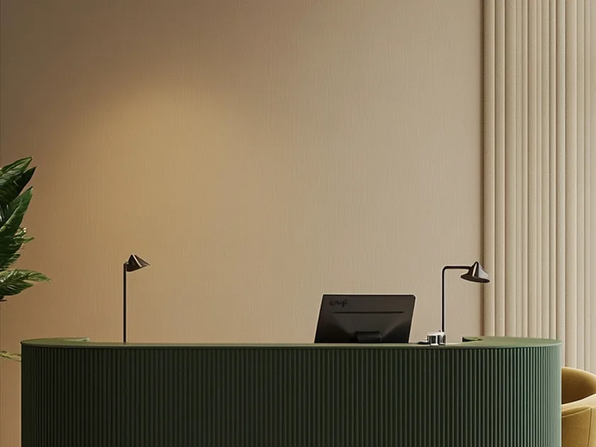 Minimalist curved green reception desk with a computer monitor, two modern black desk lamps, beige wall, and vertical beige curtains.