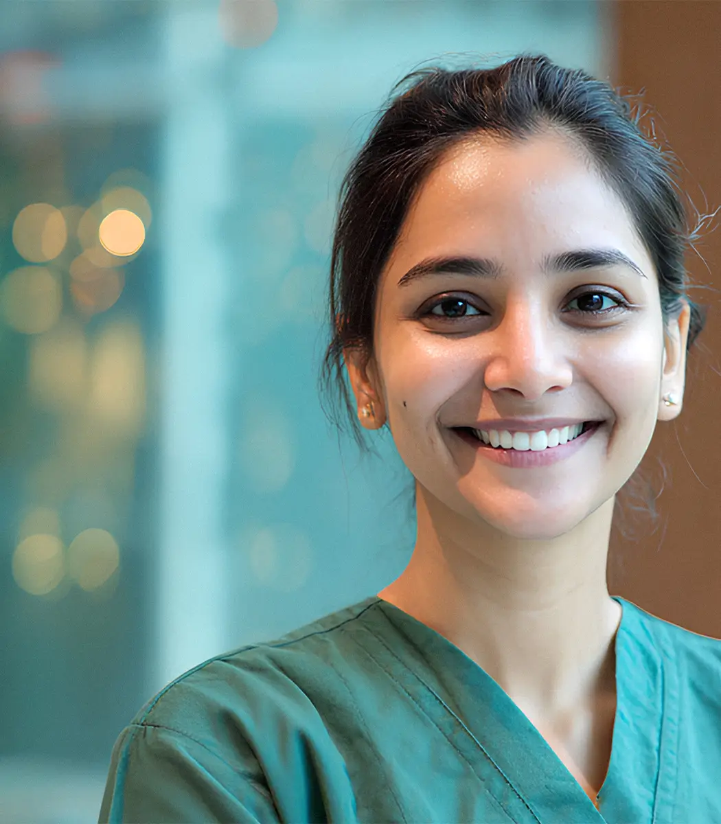 Smiling female healthcare worker wearing green scrubs with blurred background.