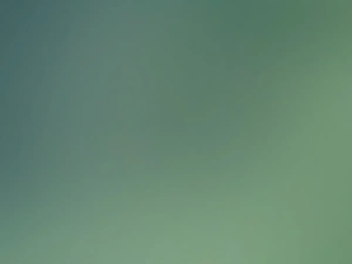 Wooden bento-style box filled with rice topped with avocado, lime wedge, small bowl of sauce, grilled salmon, cucumber salad, and sliced radishes.