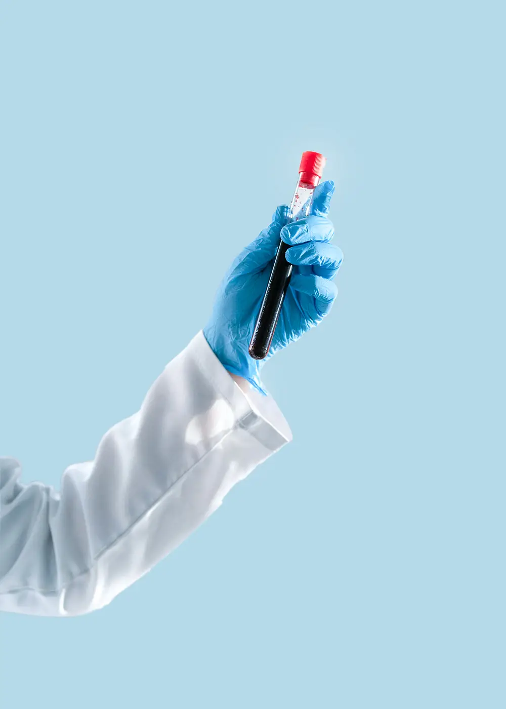 Hand wearing blue glove holding a test tube filled with dark liquid against a light blue background.