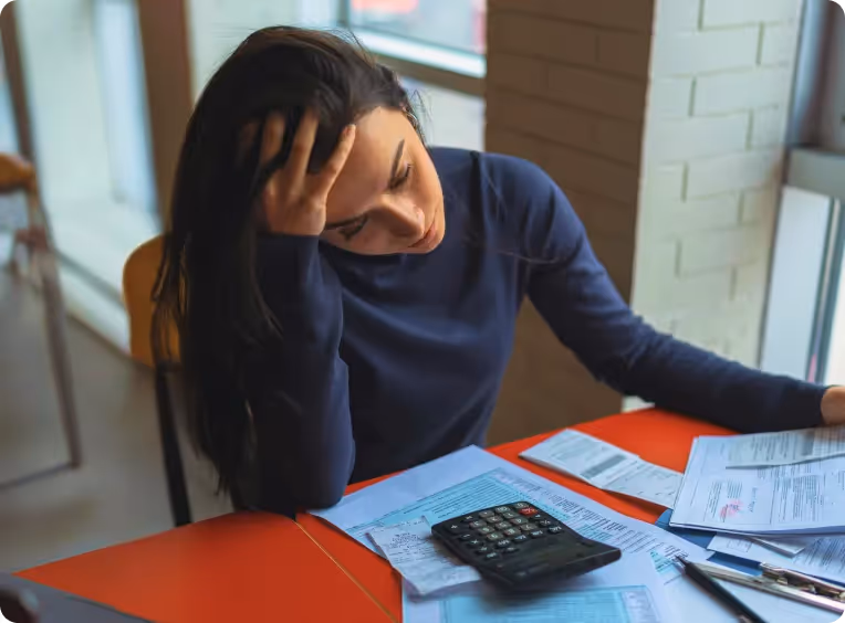 a woman holds her head in front of her bills