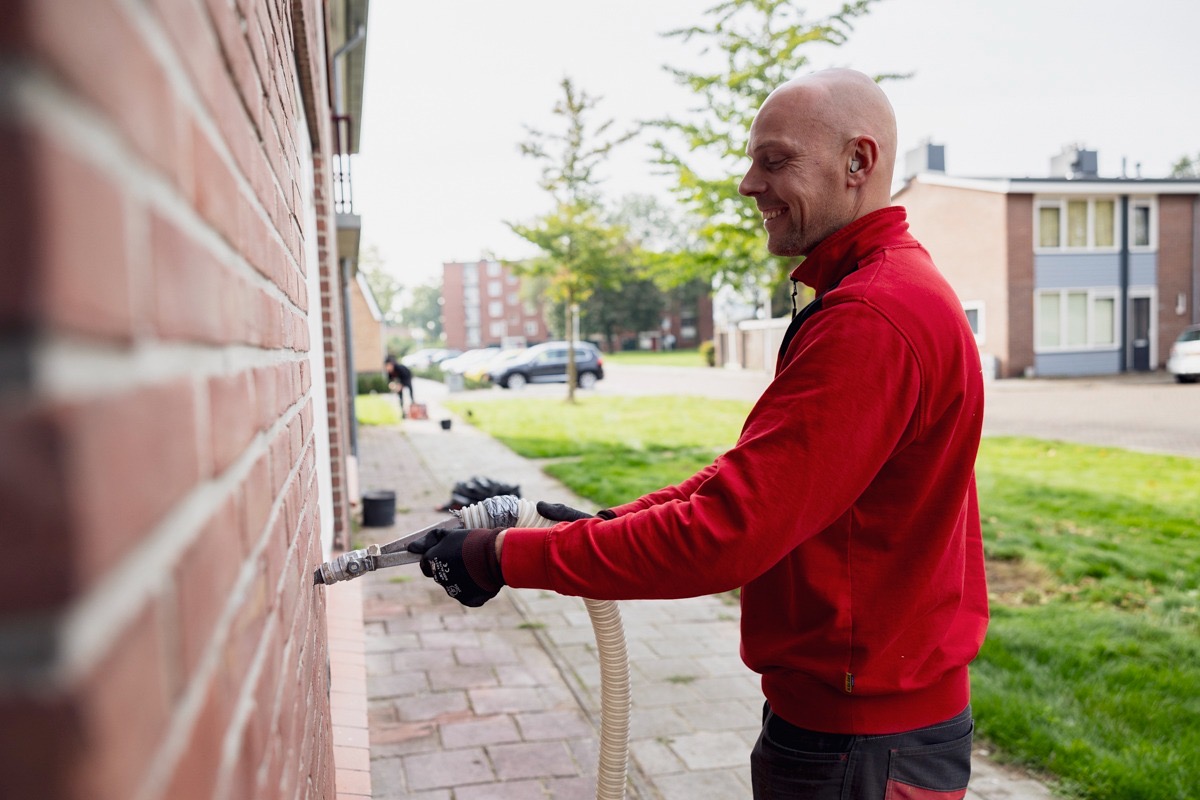 Monteur voert spouwmuurisolatie uit bij een woning — energiezuinige isolatie in uitvoering.