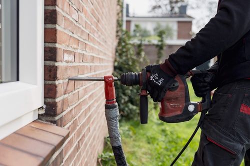 Monteur voert spouwmuurisolatie uit bij een woning — energiezuinige isolatie in uitvoering.