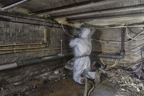 Werknemer brengt vloerisolatie aan in een kruipruimte.