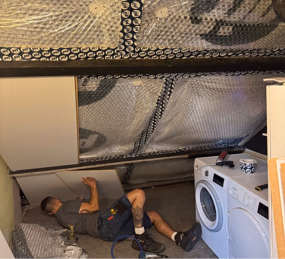 Monteur spuit isolatieschuim aan de binnenkant van een oud dak — vakkundige dakisolatie voor energiezuinige woningen.