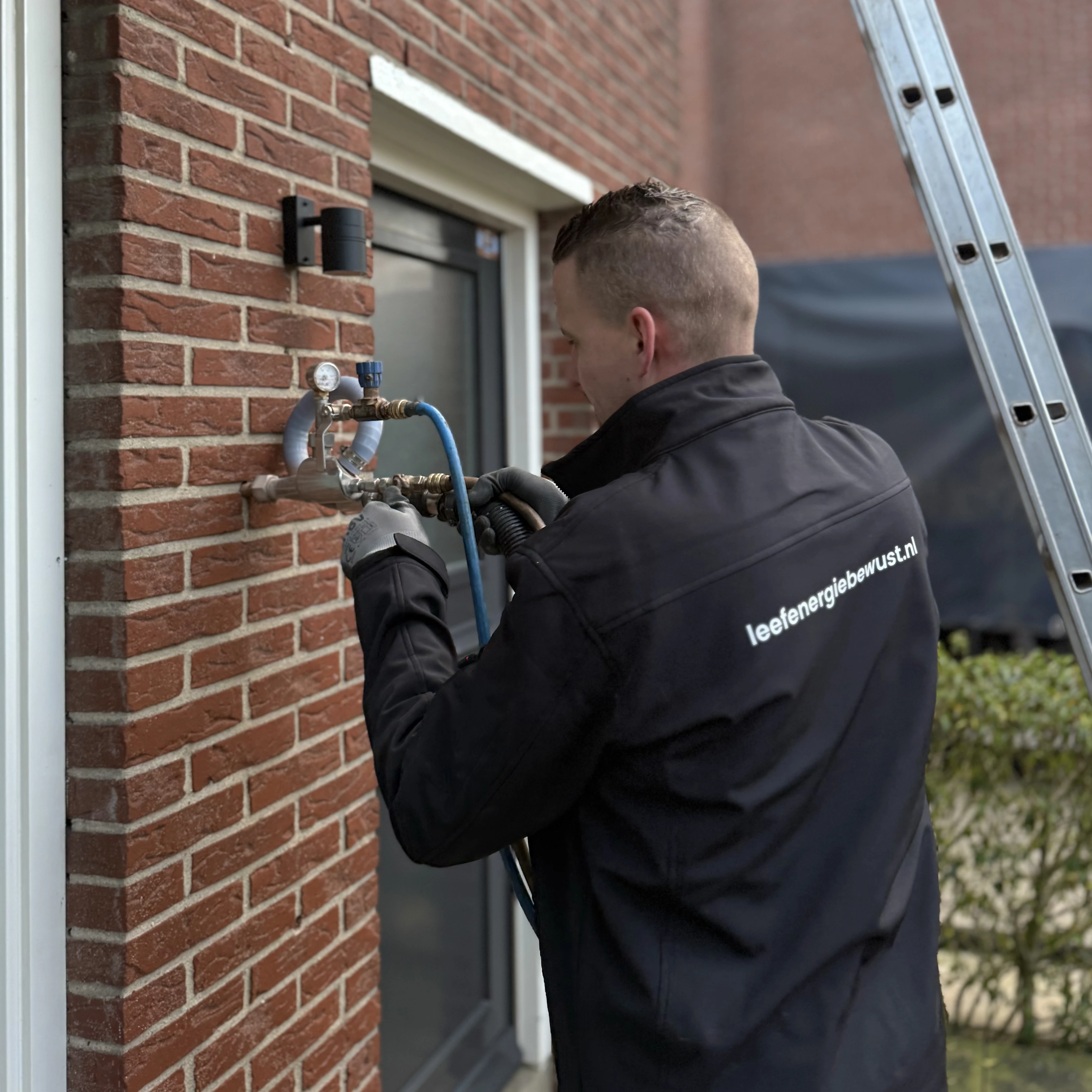 Monteur voert spouwmuurisolatie uit bij een woning — energiezuinige isolatie in uitvoering.