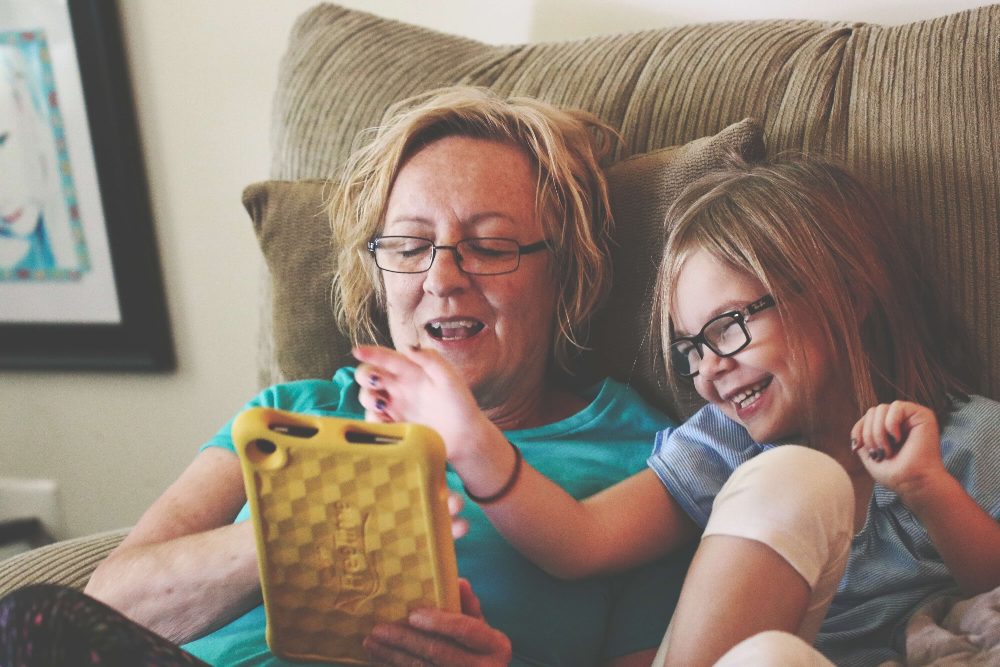 mother and daughter playing on tablet