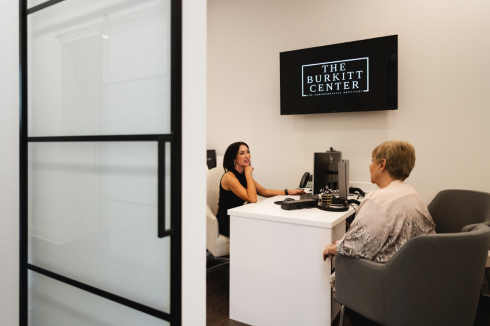Patient consultation at The Burkitt Center reception desk with dental team member.