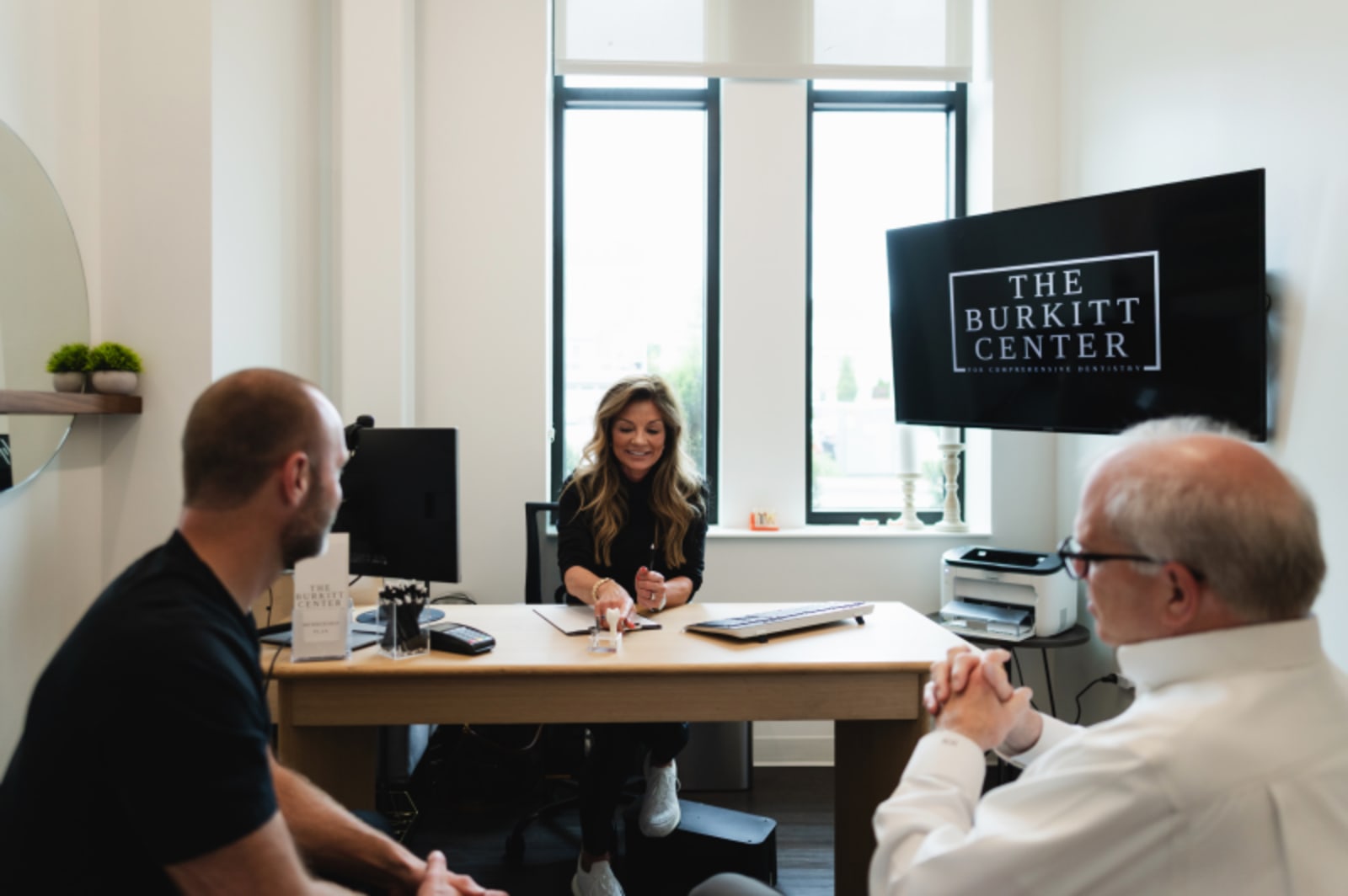 Patient consultation with dental hygienist in modern office setting discussing treatment options.