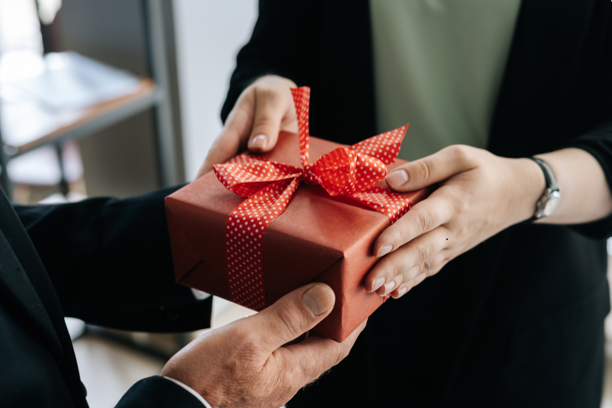 Mehrere Lebensläufe mit einer Brille darauf liegen auf einem Holztisch neben einem Laptop und einer kleinen Uhr.