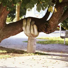 Hand sculpture holding up tree branch