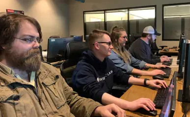 four people sitting at computers