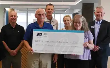 Group of people posing with large check