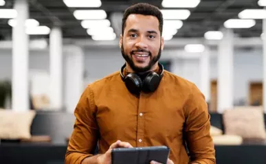 man smiling with headphones holding tablet