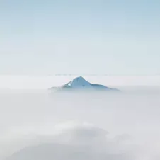 top of mountain peaking through the clouds