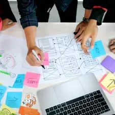 person working with laptop, papers, and post-it notes