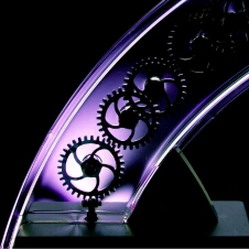 Close-up of interlocking metal gears in a curved, illuminated frame with purple lighting.