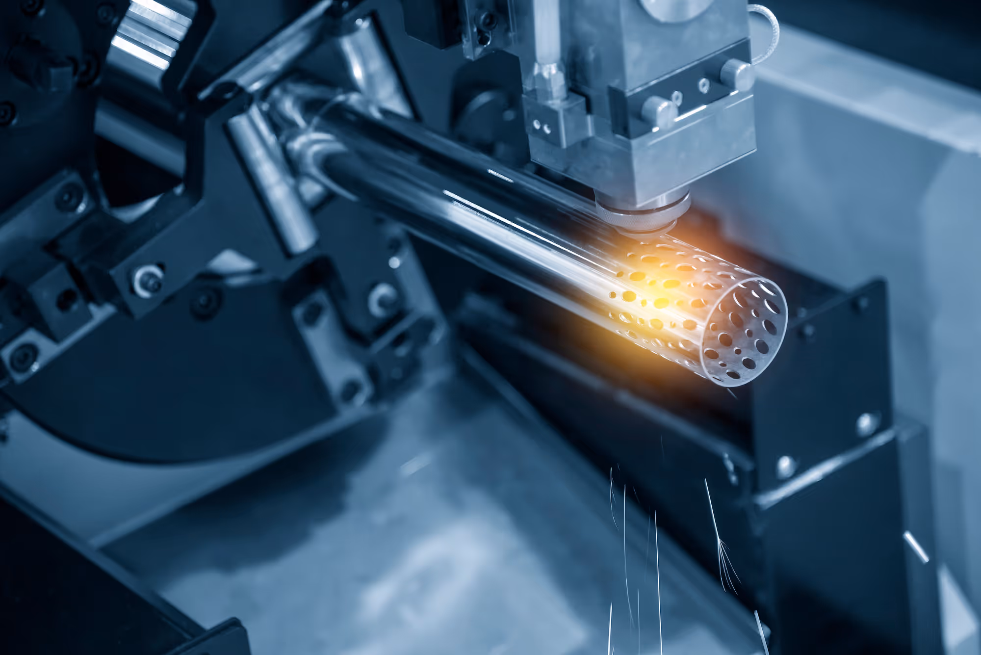 Close-up of a laser cutting machine engraving a perforated metal tube.