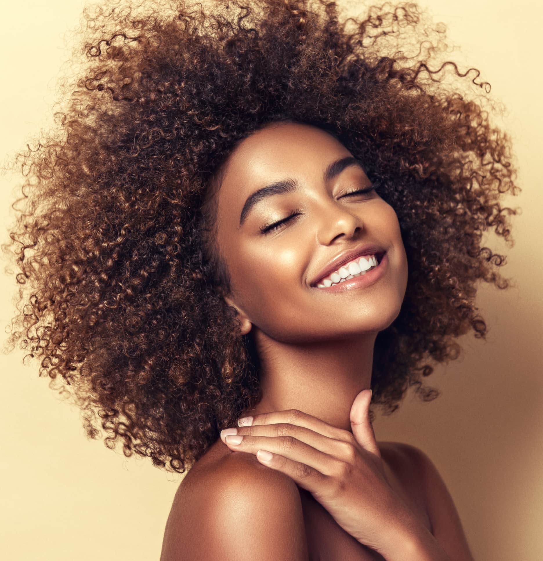 A woman smiling with her hand on her shoulder