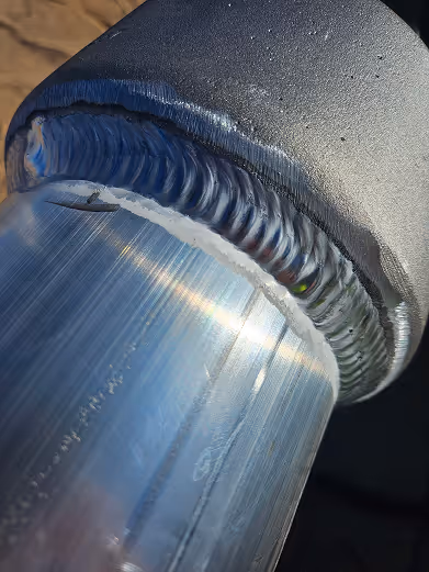 Close-up of a clean, precise metal weld seam joining two cylindrical pieces of metal.